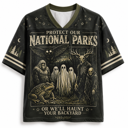 A black short-sleeve V-neck t-shirt with a detailed graphic print on the front. The graphic features a spooky national parks theme with a toad, ghosts, a skeleton, a bat, and a deer skull, accompanied by the text 'PROTECT OUR NATIONAL PARKS OR WE'LL HAUNT YOUR BACKYARD'.