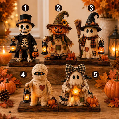 Five Halloween decorative figurines arranged on wooden pedestals in a warm, autumn-themed setting. The set includes a skeleton dressed as a top hat guest, a scarecrow in a patchwork patch hat, a ghost in a plaid witch hat, a mummy with a lantern, and a ghost in a plaid bonnet holding a glowing star.
