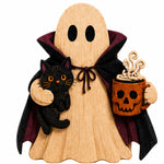 A wooden Halloween decoration shaped like a ghost in a black and burgundy cape, holding a black cat in one arm and a pumpkin skull mug with steam in the other, on a plain white background.