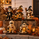 A set of five Halloween decorative figurines styled on wooden crates and stone steps outdoors. The collection includes a skeleton in a top hat, a patchwork scarecrow, a ghost with a plaid bow, a mummy, and a witch holding a broom, each holding a lantern and surrounded by pumpkins, fall leaves, and a lantern.